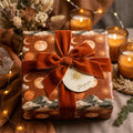 Boho celestial wrapping paper with moon patterns and a terracotta velvet bow, by Wrapped Studios.