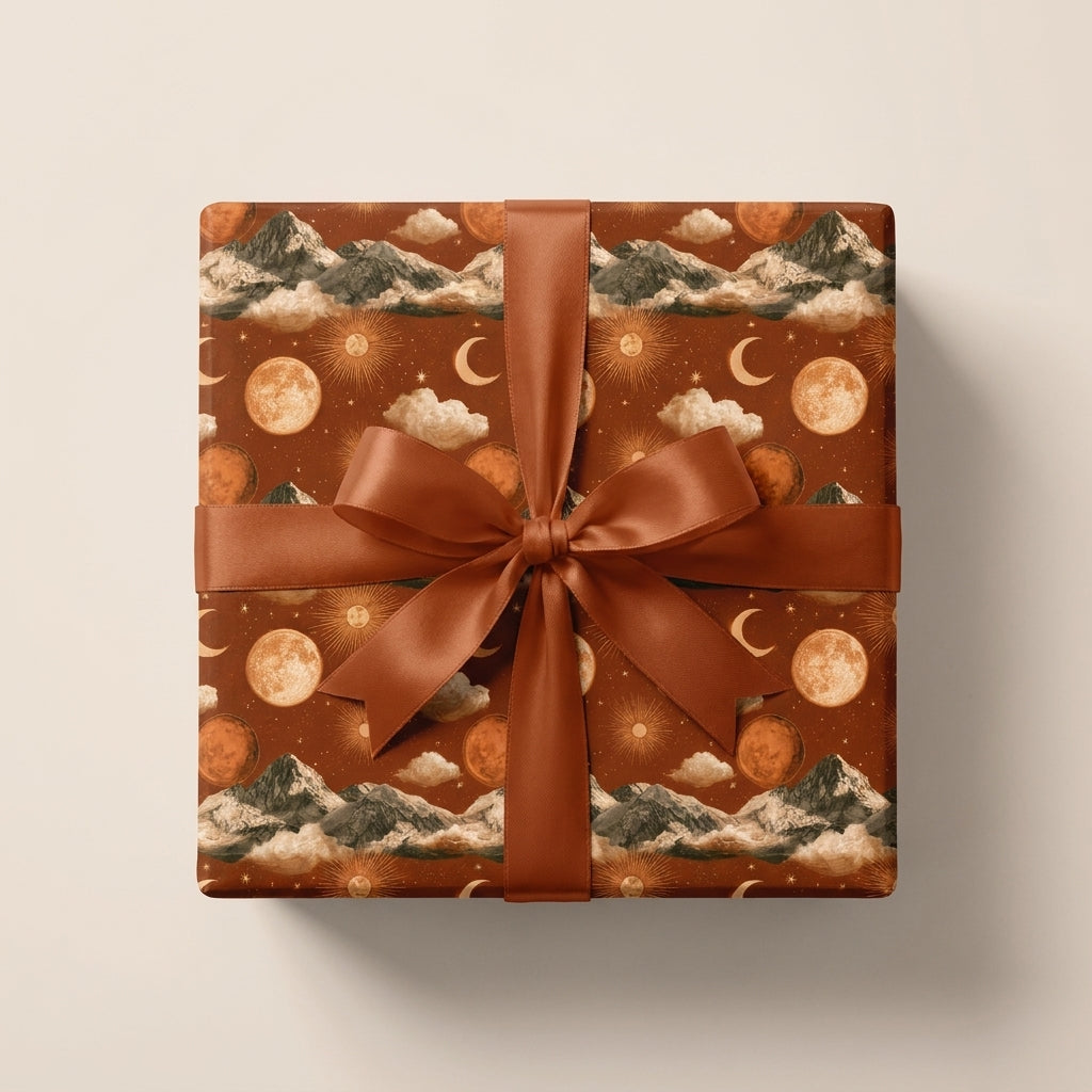 Boho celestial wrapping paper in terracotta with mountains and moons, tied with a rust bow by Wrapped Studios.