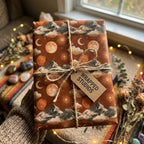 Terracotta celestial wrapping paper with mountains and moons, tied with twine by Wrapped Studios.
