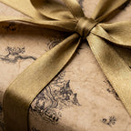 Vintage kraft wrapping paper with a rustic landscape print and gold satin ribbon by Wrapped Studios.