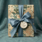 Vintage world map wrapping paper with dusty blue satin ribbon and gift tag by Wrapped Studios.
