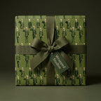 Military wrapping paper with a saluting soldier pattern and olive green ribbon bow by Wrapped Studios.