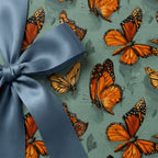 Elegant gift box wrapped in butterfly print wrapping paper with a blue satin bow.