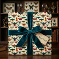 Elegant gift wrapped in moth-themed vintage wrapping paper with teal velvet ribbon and "A Rare Find" tag.