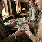 A flat gift wrapped in decorative moth patterned wrapping paper with a twine bow exchanged between 3 people.
