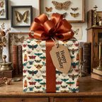 Vintage-style birthday wrapping paper with moth pattern, tied with a copper-colored ribbon and a "Happy Birthday" tag.