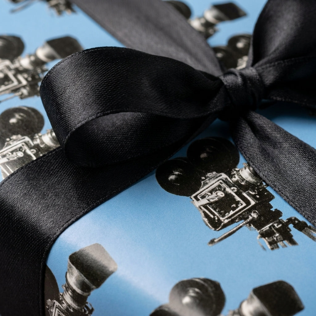 Retro movie camera wrapping paper in blue with a black satin ribbon by Wrapped Studios.