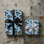 Retro cinema wrapping paper in light blue with vintage movie cameras on gift boxes by Wrapped Studios.