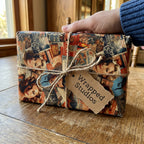 Rectangular gift wrapped in vintage-style wrapping paper featuring movie stars and tied with rustic twine.