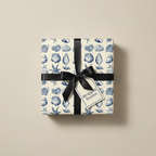 Gift box wrapped in cream & blue seashell wrapping paper, tied with a black satin ribbon.