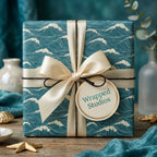 Luxury teal ocean wave wrapping paper with a cream satin ribbon bow and Wrapped Studios gift tag.
