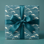 Teal ocean wave wrapping paper on a square gift box with a satin bow by Wrapped Studios.