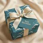 Teal ocean wave wrapping paper with cream ribbon and "Just Because" tag, luxury gift wrap by Wrapped Studios.