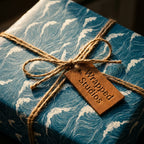 Coastal blue ocean wave wrapping paper by Wrapped Studios, tied with a rustic jute twine bow on a gift box.