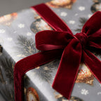 Luxury Christmas wrapping paper with vintage ornaments and a red velvet bow by Wrapped Studios.