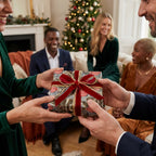 Luxury Christmas wrapping paper with red velvet ribbon by Wrapped Studios, being exchanged at a holiday party.
