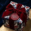 Luxury Christmas wrapping paper with a winter owl pattern and red velvet bow by Wrapped Studios.