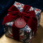 Luxury Christmas wrapping paper with a winter owl pattern and red velvet bow by Wrapped Studios.