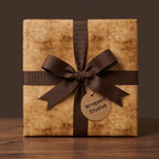Rustic vintage wrapping paper on a square gift box with a brown ribbon bow, by Wrapped Studios.