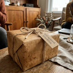 Rustic brown kraft wrapping paper with twine bow and Wrapped Studios tag on a cozy wooden table.