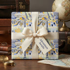 Paris travel wrapping paper with cream ribbon and "Adventure Awaits" tag by Wrapped Studios.