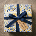Vintage Paris wrapping paper in blue and yellow, tied with a navy bow and Wrapped Studios tag.