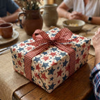 Patriotic star wrapping paper with a red gingham bow on a rustic gift box by Wrapped Studios.