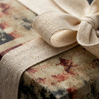 Vintage patriotic wrapping paper with a cream fabric bow on a rustic gift box by Wrapped Studios.