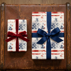 Patriotic American flag wrapping paper with red and blue bows on a vintage suitcase by Wrapped Studios.