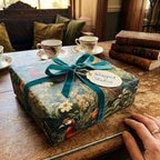 Elegant gift wrapped in floral wrapping paper from Wrapped Studios, with a teal velvet ribbon and tag.