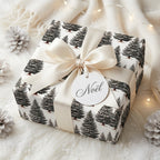 Luxury pine tree Christmas wrapping paper with a cream satin bow on a gift box by Wrapped Studios.