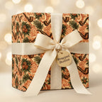 Vintage holiday wrapping paper with a pipe and pine pattern and cream bow by Wrapped Studios.