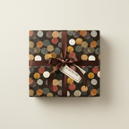 Square gift wrapped in rustic polka dot wrapping paper with a brown satin ribbon and tag.