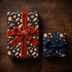 Outer space wrapping paper with rocket and planet patterns on gifts with elegant bows by Wrapped Studios.