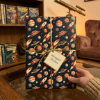 Retro space rocket wrapping paper with planets and gold ribbon, by Wrapped Studios.