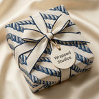 Nautical wrapping paper with navy blue rope pattern and elegant ribbon bow by Wrapped Studios.