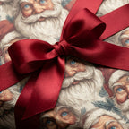Christmas gift wrapped in Santa face paper and a lush red satin ribbon.