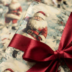 Vintage Santa Christmas wrapping paper with a red satin bow. Luxury holiday gift wrap by Wrapped Studios.
