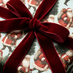 Vintage Santa Christmas wrapping paper tied with a luxury red velvet ribbon bow by Wrapped Studios.