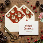 Vintage Santa Claus Christmas card and envelope liners by Wrapped Studios on a rustic wood table.