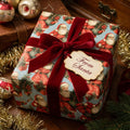 Vintage Santa Christmas wrapping paper by Wrapped Studios with a red velvet bow and "From Santa" tag.