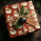 Vintage Santa Christmas wrapping paper on a rustic gift with twine, pine, and bell by Wrapped Studios.
