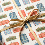 Vintage travel wrapping paper with watercolor suitcase pattern and gold ribbon bow by Wrapped Studios.