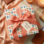 Vintage travel wrapping paper with suitcase print and coral pink bow by Wrapped Studios.