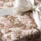Luxury vintage toile wrapping paper in brown and cream with a white satin bow by Wrapped Studios.