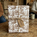 Brown vintage toile wrapping paper with a rustic twine bow and gift tag by Wrapped Studios.
