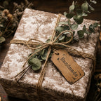 Vintage toile wrapping paper on a gift with twine, eucalyptus, and handmade tag by Wrapped Studios.