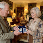 Senior couple exchanging a gift in elegant blue toile Christmas wrapping paper by Wrapped Studios.