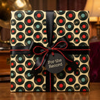 Retro music themed vinyl record wrapping paper with a black bow by Wrapped Studios.