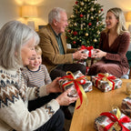 Family exchanging gifts in Christmas wrapping paper with red and gold ribbons, by Wrapped Studios.